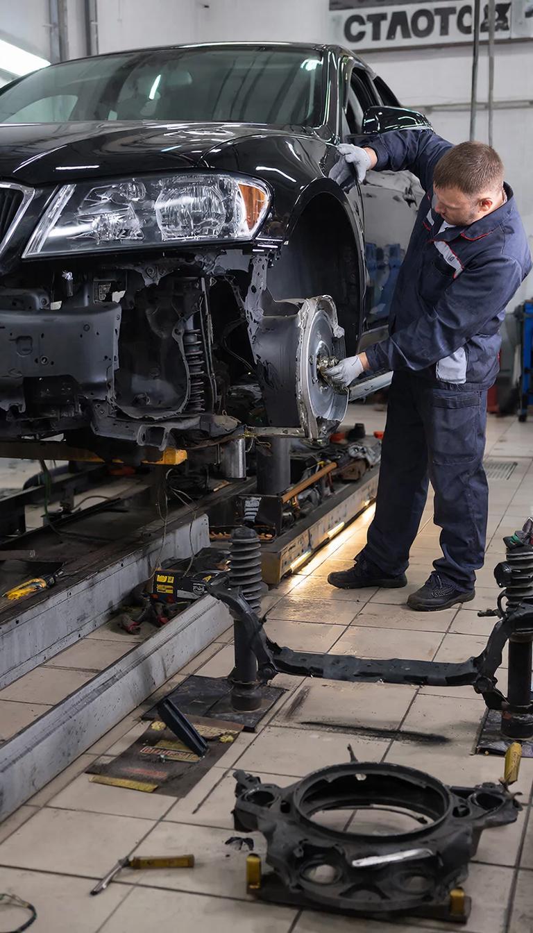 Автомеханник ремонтирует подвеску автомобиля