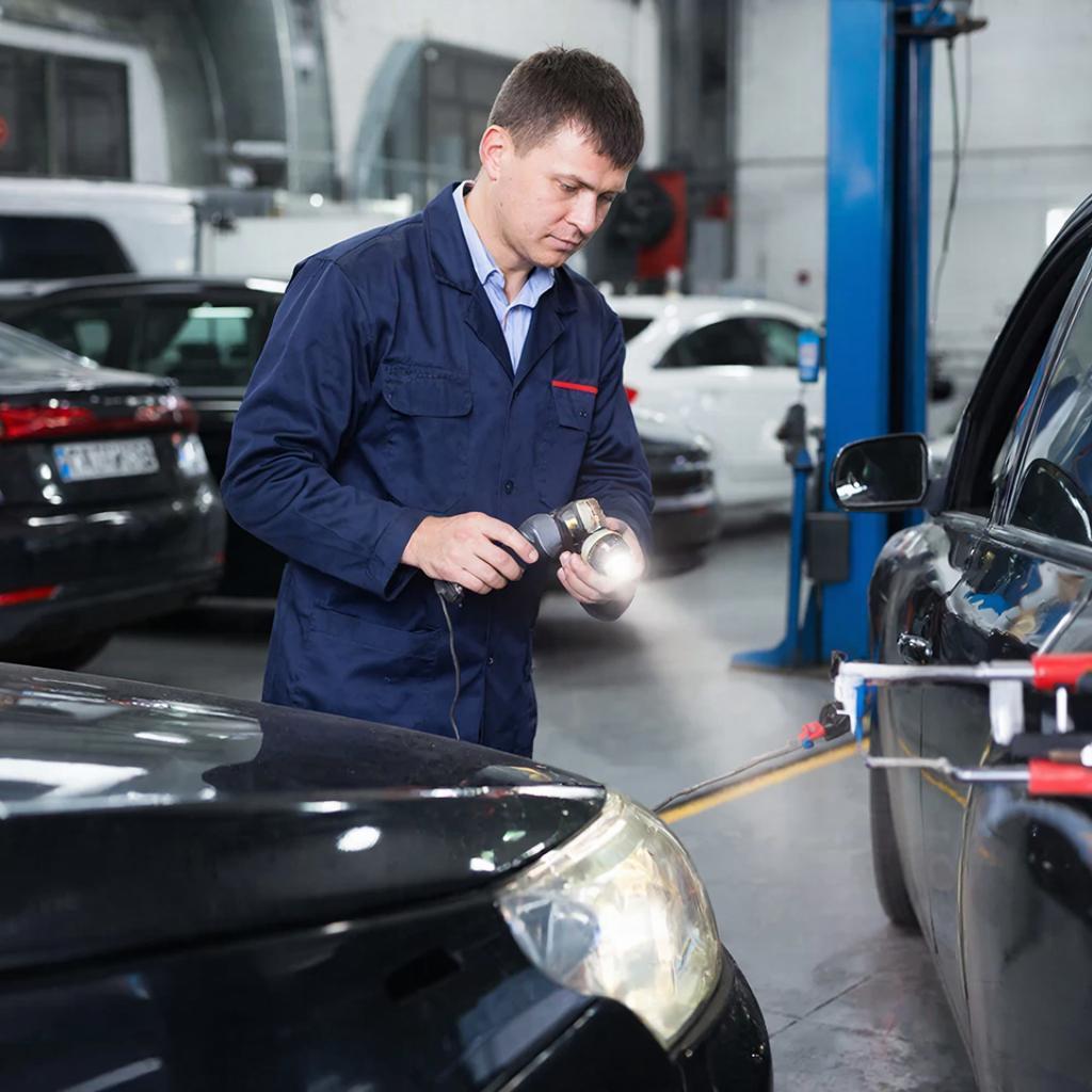 Мастер меняет лампочку фары автомобиля