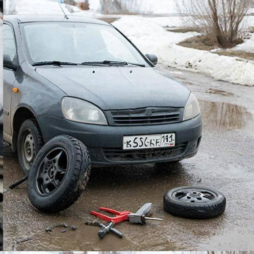 изображение автомобиля , на котором меняют колесо на улице
